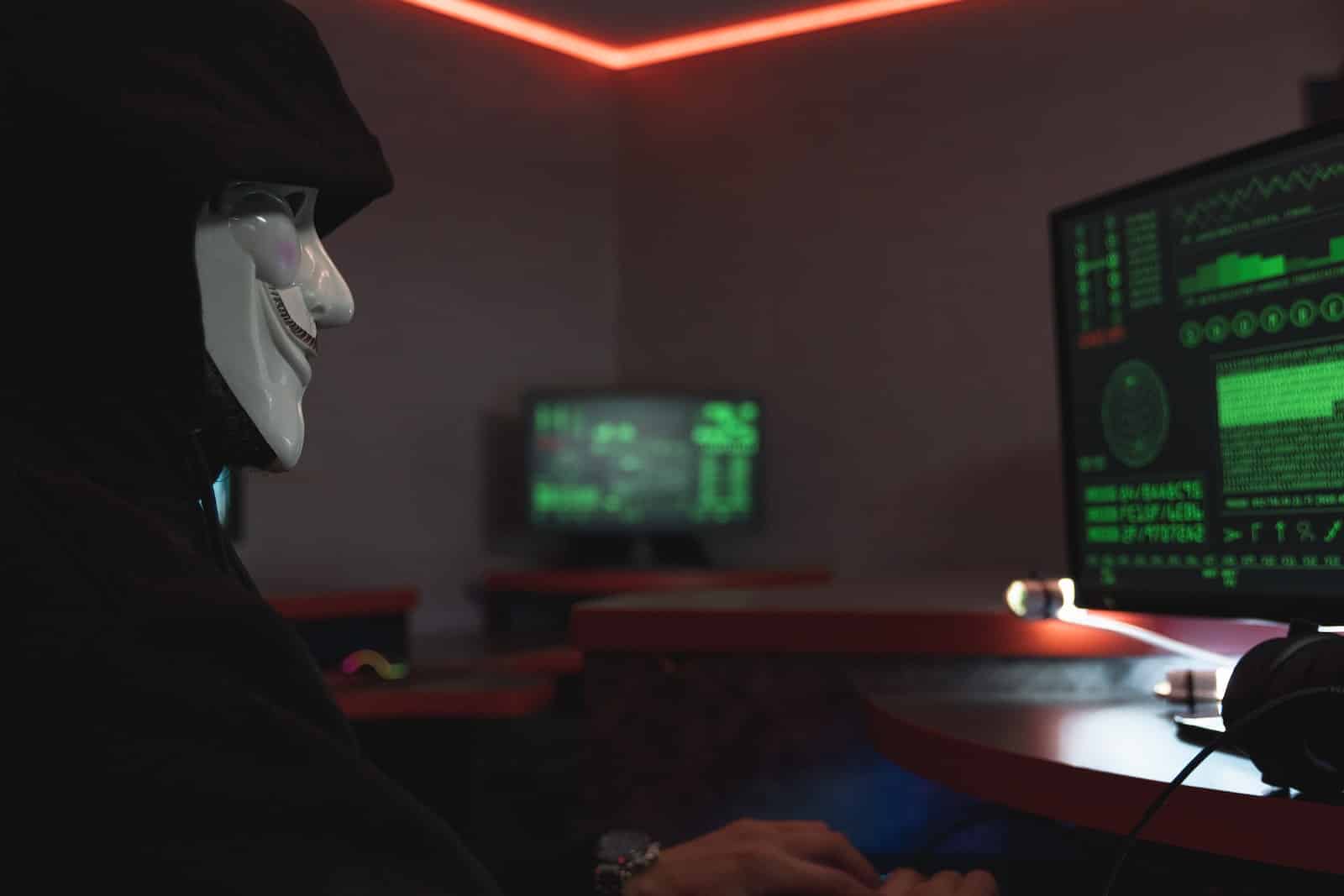 Een persoon met een masker die een computer gebruikt